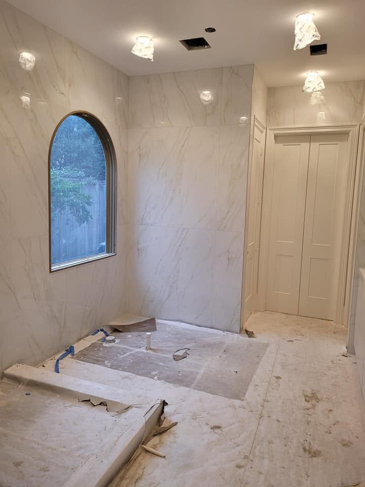 Unfinished bathroom with marble walls, arched window, recessed lighting, and cream-colored cabinetry