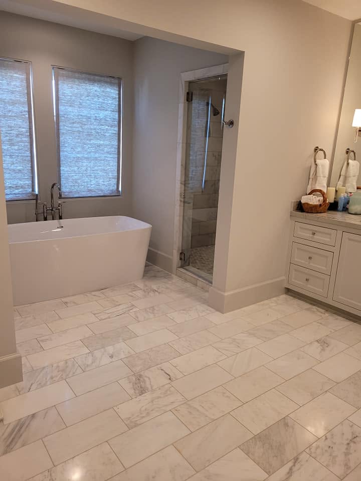 Modern luxury bathroom with white freestanding tub, walk-in shower, marble tile flooring, and vanity