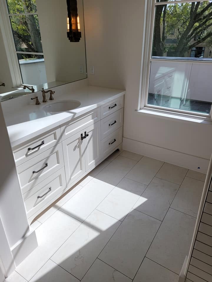 Modern bathroom with white vanity, single sink, large mirror, and gray tile flooring