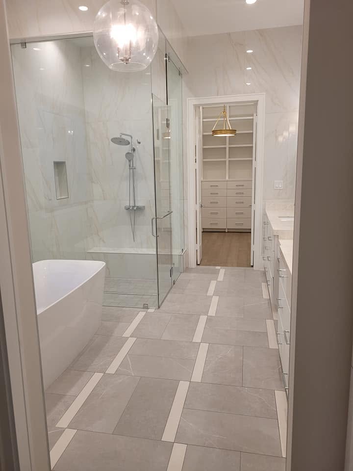Modern luxury bathroom with marble tile flooring, walk-in shower, freestanding tub, and built-in closet storage