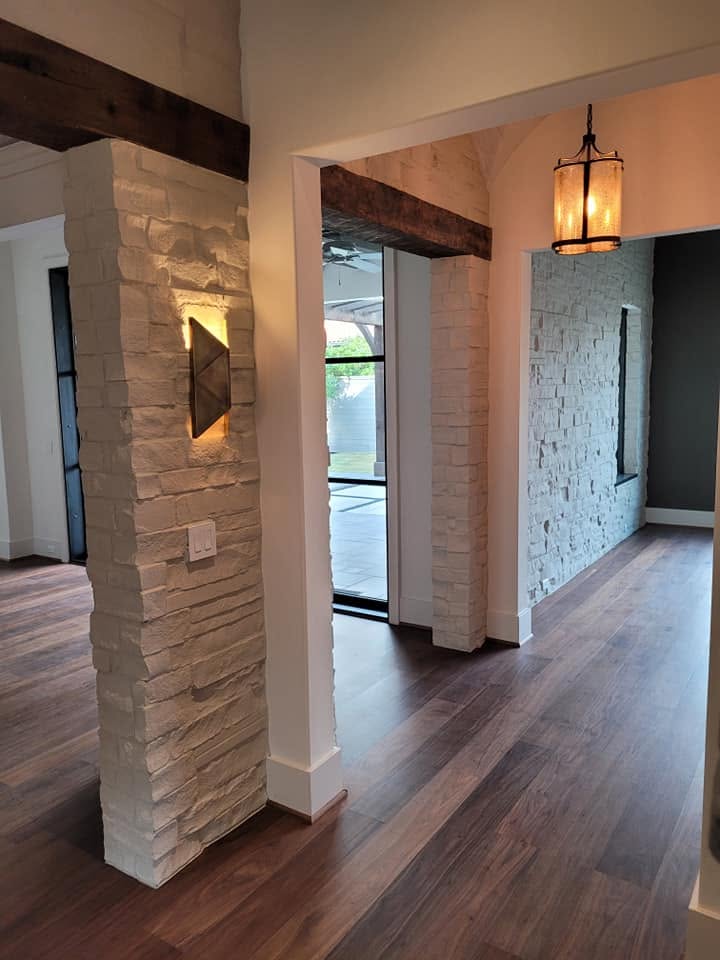 Modern entryway with stone columns, wood flooring, and pendant lighting