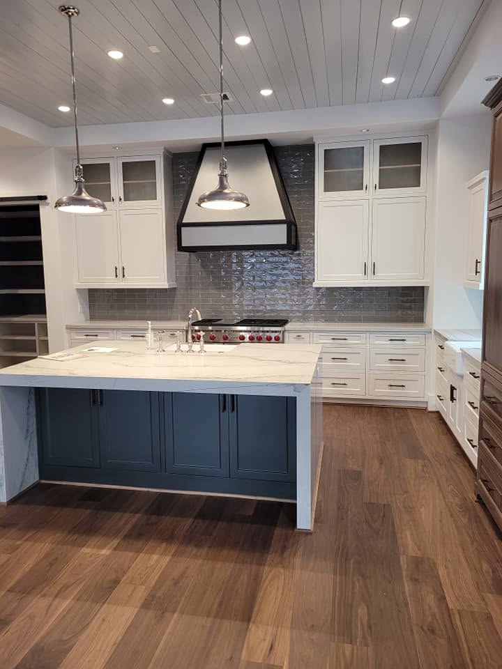 Modern kitchen with white cabinetry, blue island, gray subway tile backsplash, and pendant lighting