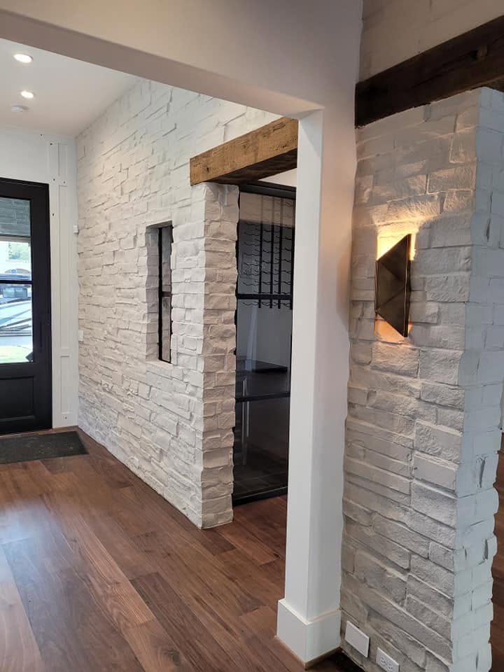 Modern entryway with white brick walls, wooden beam, dark doorway, and warm lighting
