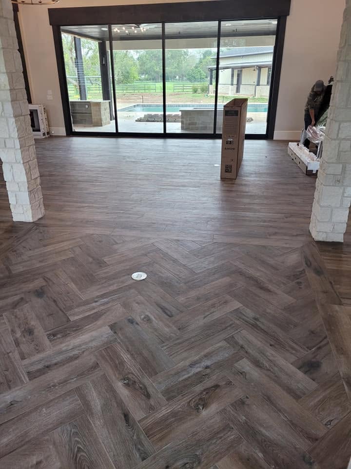 Modern home interior with herringbone wood flooring and black-framed glass doors overlooking pool and patio