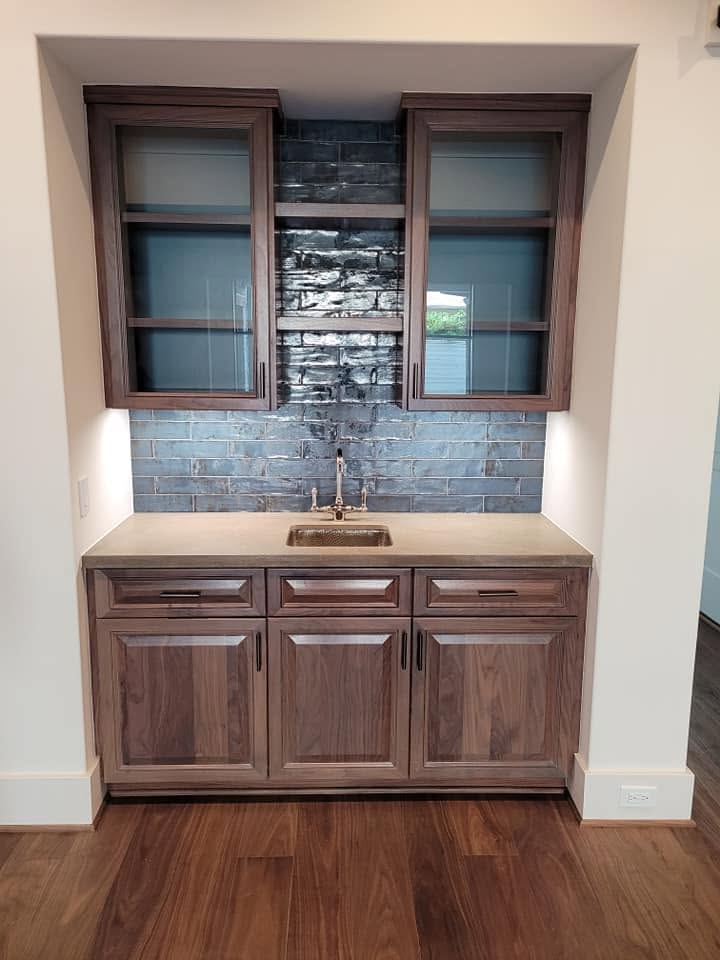 Built-in wet bar with dark wood cabinetry, granite countertop, and blue subway tile backsplash