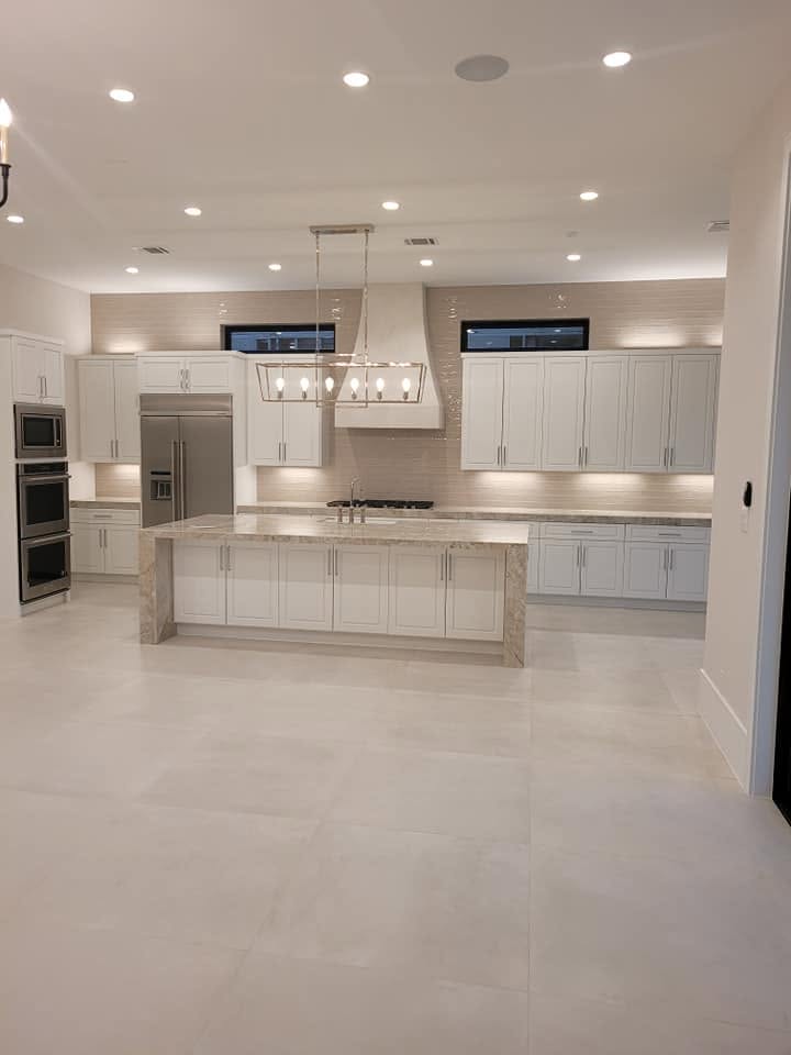 Modern white kitchen with island, stainless steel appliances, and recessed lighting