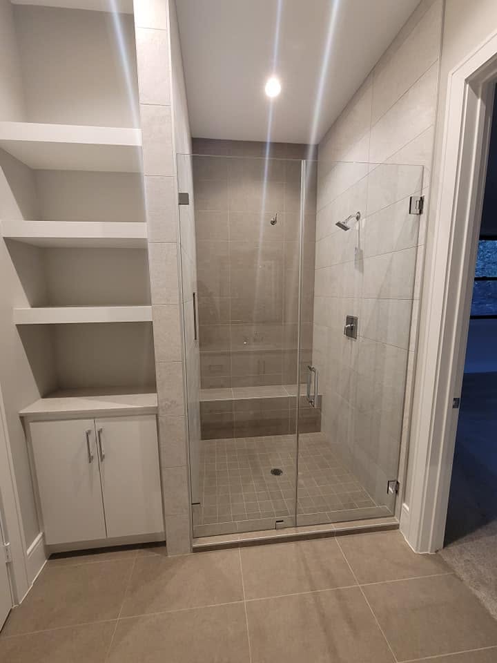 Modern bathroom with walk-in shower, glass enclosure, and built-in storage shelving