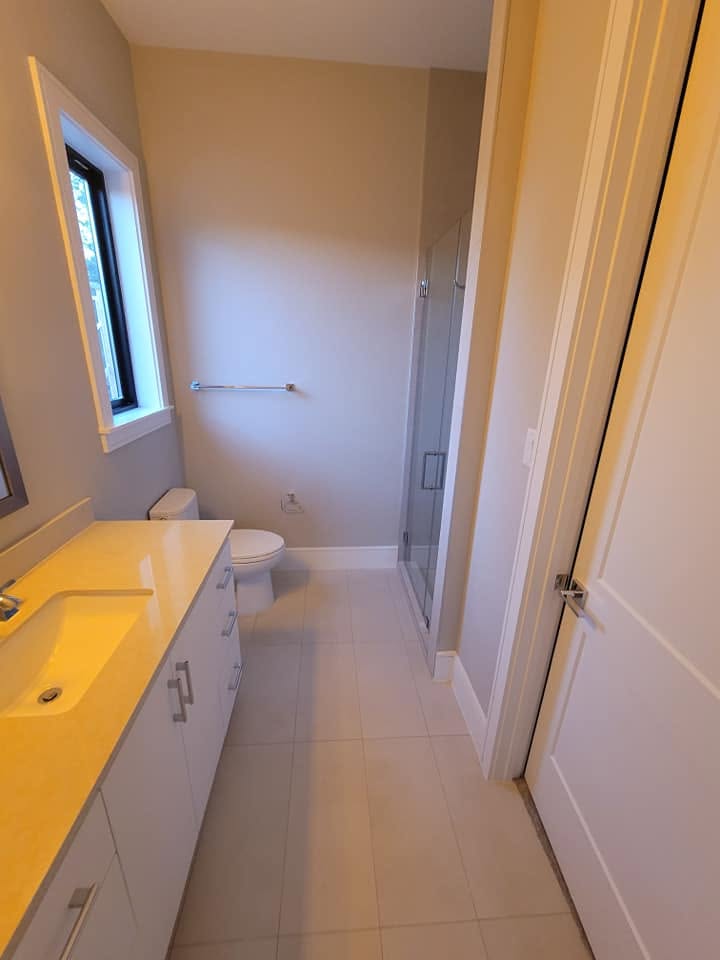 Modern bathroom with yellow vanity, toilet, and walk-in shower with glass enclosure