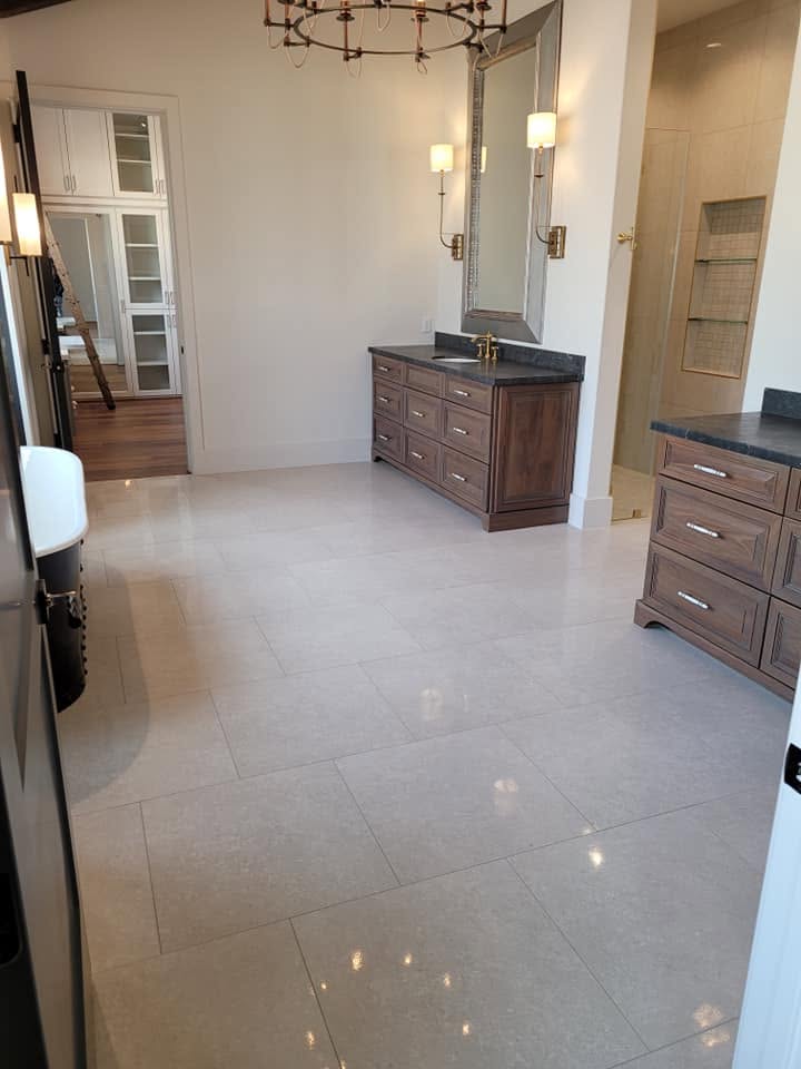 Spacious master bathroom with dual vanities, large mirror, polished tile flooring, and wooden cabinetry