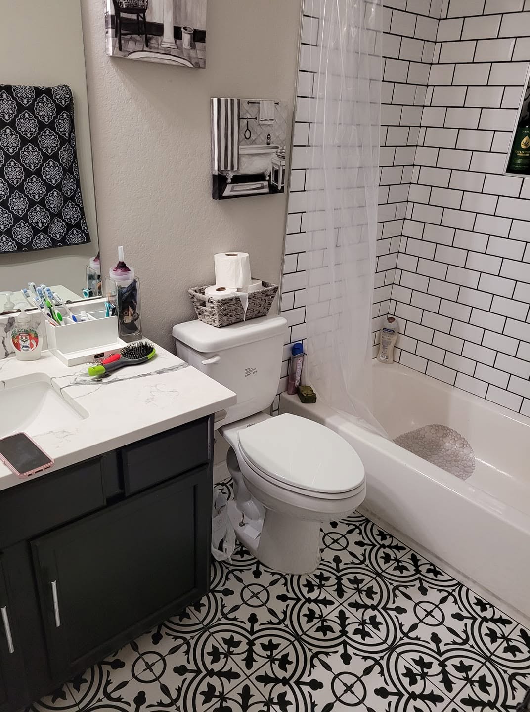 Modern bathroom with black vanity, white subway tile, patterned floor, and organized countertop