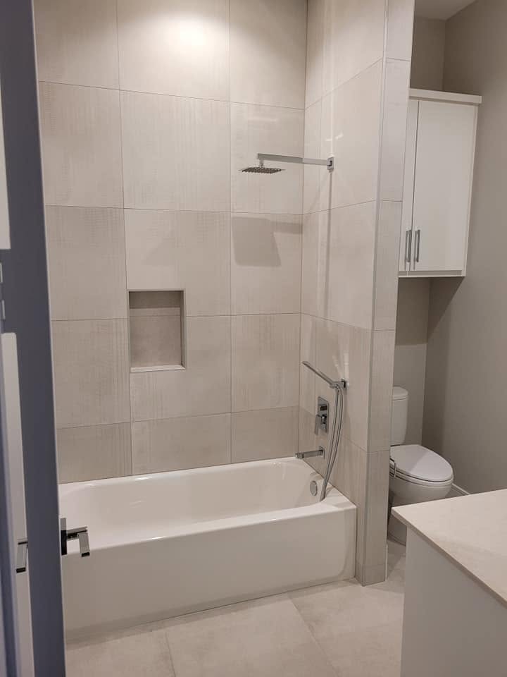 Modern bathroom with white tile shower enclosure, soaking tub, and toilet
