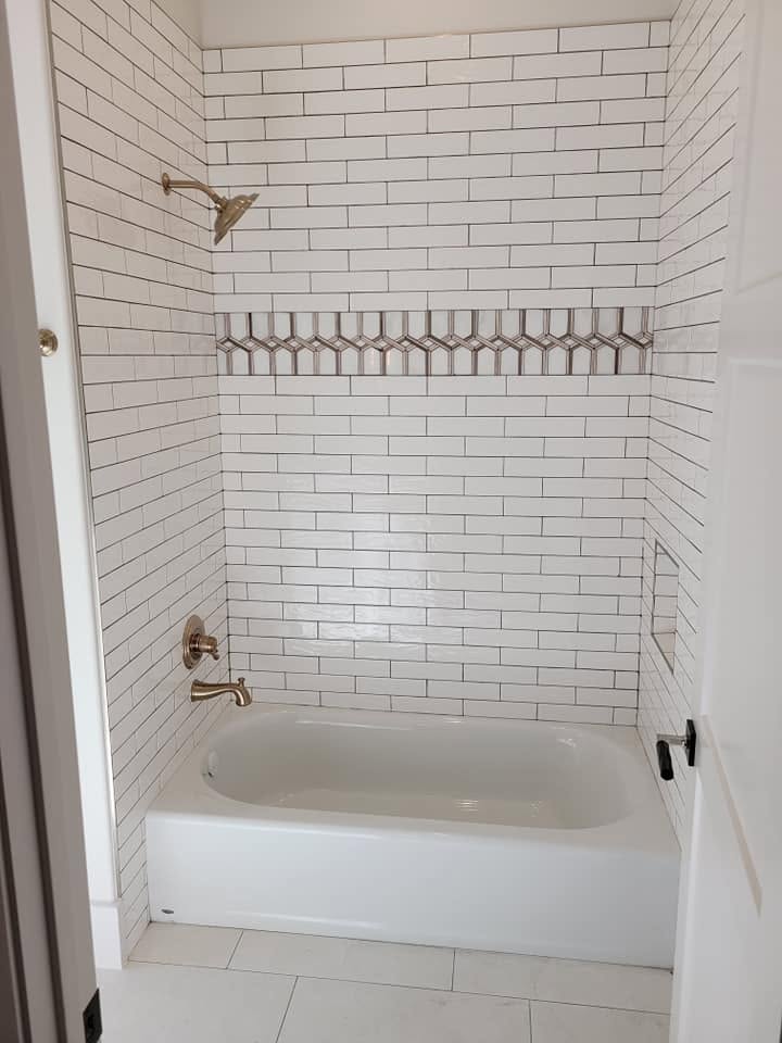 Modern white subway tile shower surround with brass fixtures and linear drain