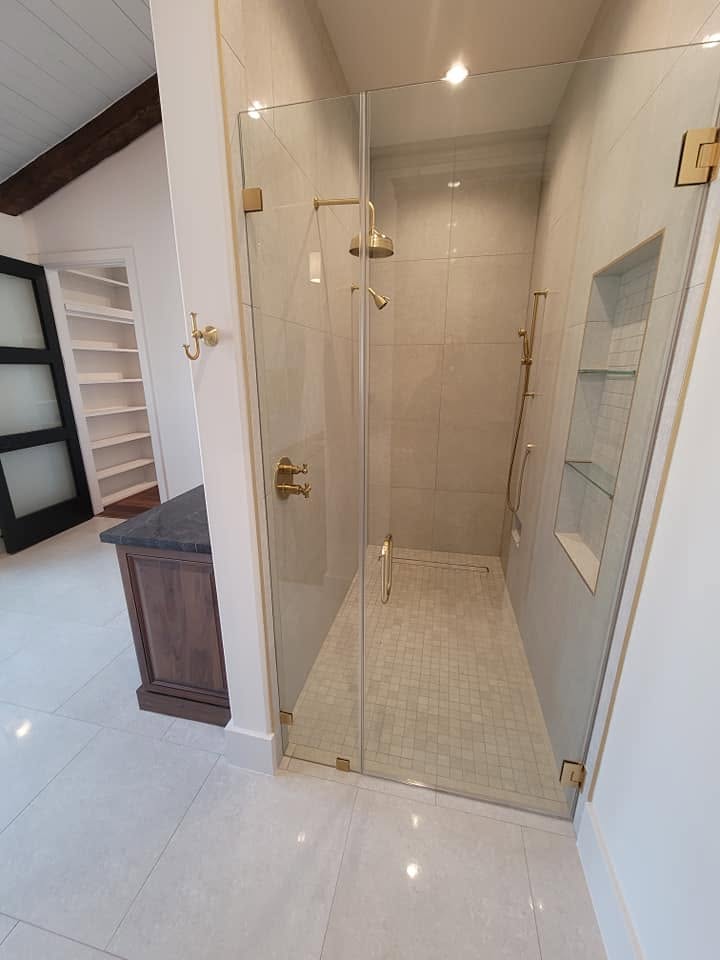 Modern frameless glass shower enclosure with brass fixtures in luxury bathroom