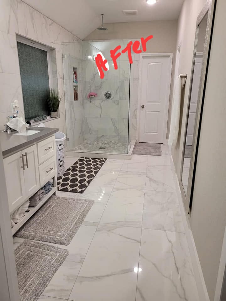 Modern bathroom with marble tile flooring, white vanity, glass shower enclosure, and geometric patterned bath mat