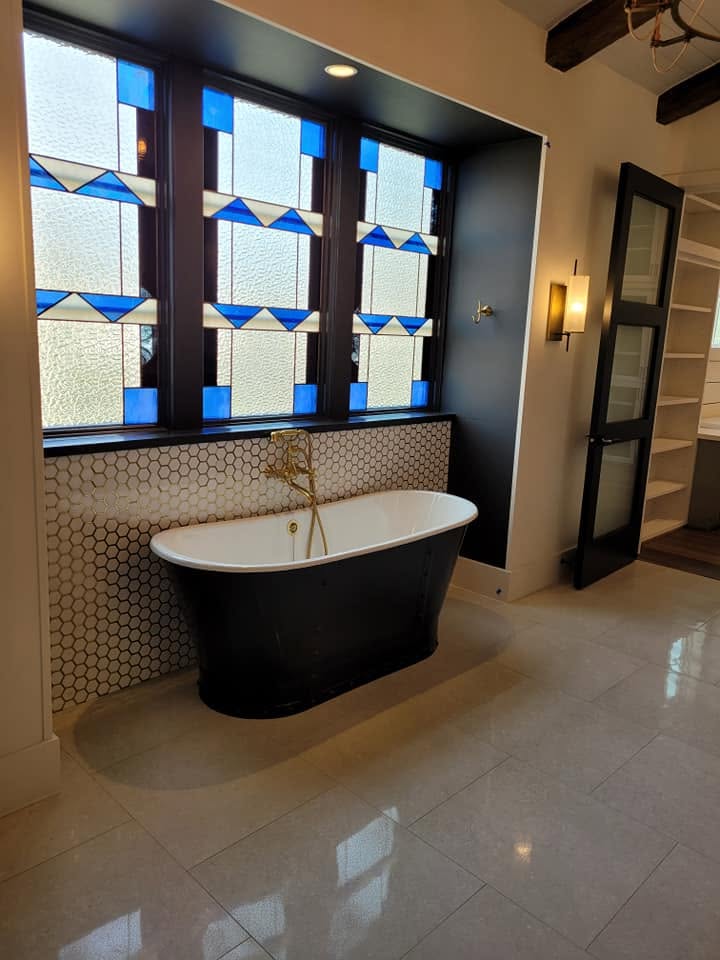 Modern bathroom with black freestanding tub and stained glass window