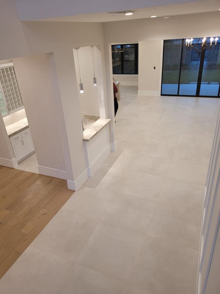 Modern bathroom showroom with white cabinetry, tile flooring, and large windows at dusk