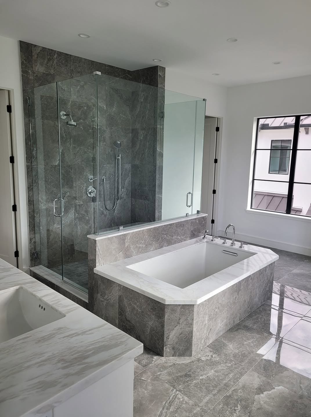 Modern luxury bathroom with walk-in shower, soaking tub, and marble finishes